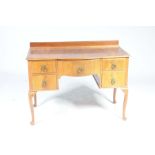 A mid 20th Century walnut Queen Anne style dressing table Having a central convex frieze drawer