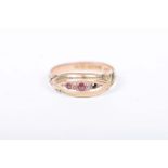 An Edwardian ruby and diamond ring The graduated stones to a scroll shank, one stone deficient,