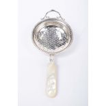 A silver and mother of pearl tea strainer Of circular form,