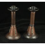 A pair of A E Jones Arts & Crafts copper candlesticks Each having planished decoration with applied