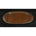 An A E Jones Arts & Crafts copper tray Of oval form having white metal reeded border and planished
