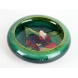 A Walter Moorcroft pottery dished bowl Decorated in the Orchid pattern on a green ground,