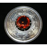 An Arts & Crafts Scottish silver brooch Of circular form with central amber coloured stone,