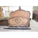 A late 19th early 20th Century French oak bed The shaped headboard with a scrolling leaf crest,