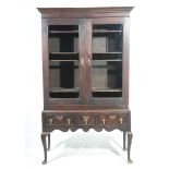 A 17th Century and later glazed oak cabinet on stand With a moulded cornice above two glazed doors