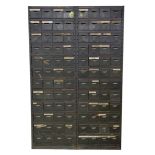 An industrial painted metal storage cabinet With an arrangement of twelve rows of eight small tray
