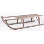 A vintage wooden sledge Of traditional form with slatted top and arched lower rails,