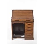 An early 20th Century oak roll top single pedestal desk With an S shaped tamber front enclosing a