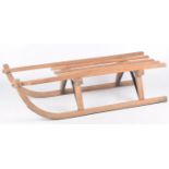 A vintage German wooden sledge Of typical form with curved lower rails and slatted seat,