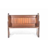 A early 20th Century pitch pine pew of small proportions With a panel back supported on two shaped
