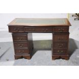 A reproduction mahogany twin pedestal serpentine desk The serpentine moulded top inset with a green