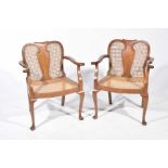 A pair of 20th Century walnut and rattan elbow chairs Each chair with a central vase shaped splat