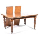 An Edwardian light oak extending dining table The rectangular top with canted corners and two extra