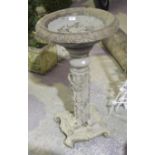 A reconstituted stone bird bath The circular top with shallow well and moulded with flower head