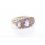 An amethyst three stone ring The graduated oval shaped amethyst in graduated form, in 9k gold,