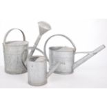 A set of three vintage galvanized watering cans Each of typical form with elongated spout and loop