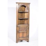 A good quality reproduction oak free standing corner cabinet With a moulded cornice above a carved