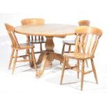 A pine circular pedestal kitchen table and four kitchen chairs The rustic pine table supported on a