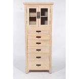 A contemporary limed oak storage cabinet With a slab top above two glazed doors enclosing a single