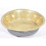 A large 19th Century circular brass bowl The base with two areas of riveted repair, 56cm diameter.