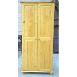 A modern pine two door wardrobe Raised upon ball feet, 81x178x53cm.
