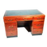 A mid 20th Century mahogany kneehole writing desk With a black inset writing surface above three