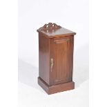 A Victorian mahogany pot cupboard With a shaped pediment above a single panelled door enclosing a