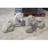 A near pair of reconstituted stone recumbent lion garden ornaments Each modelled with front paws