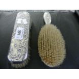 Two contintental white metal backed dressing table brushes