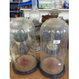 Three clear glass domes on circular wooden bases.
