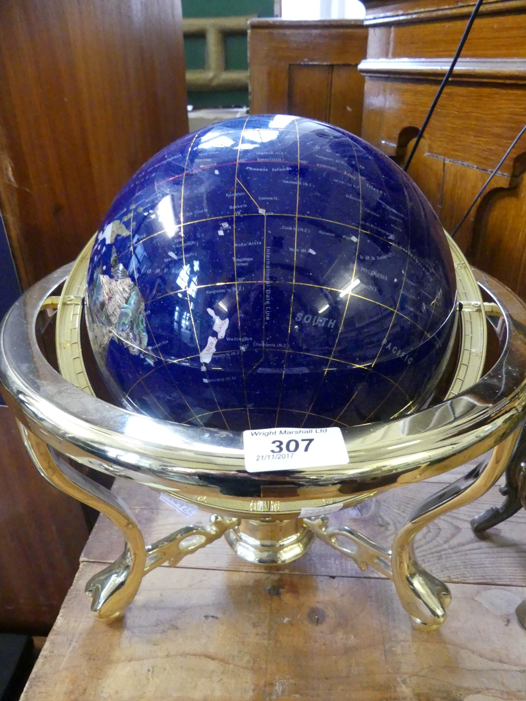 A modern hardstone and shell inlaid globe on brass finished stand.