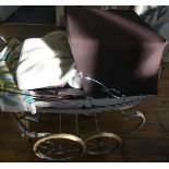 A vintage Silver Cross pram containing modern rubber bodied doll and various accessories.