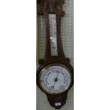 A late 19th Century oak cased aneroid barometer and thermometer combination with carved detail.