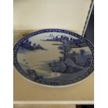 A Japanese blue and white circular charger, decorated with a landscape scene.