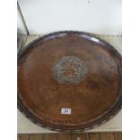 A large Hugh Wallace hammered copper circular tray with central silvered armorial.