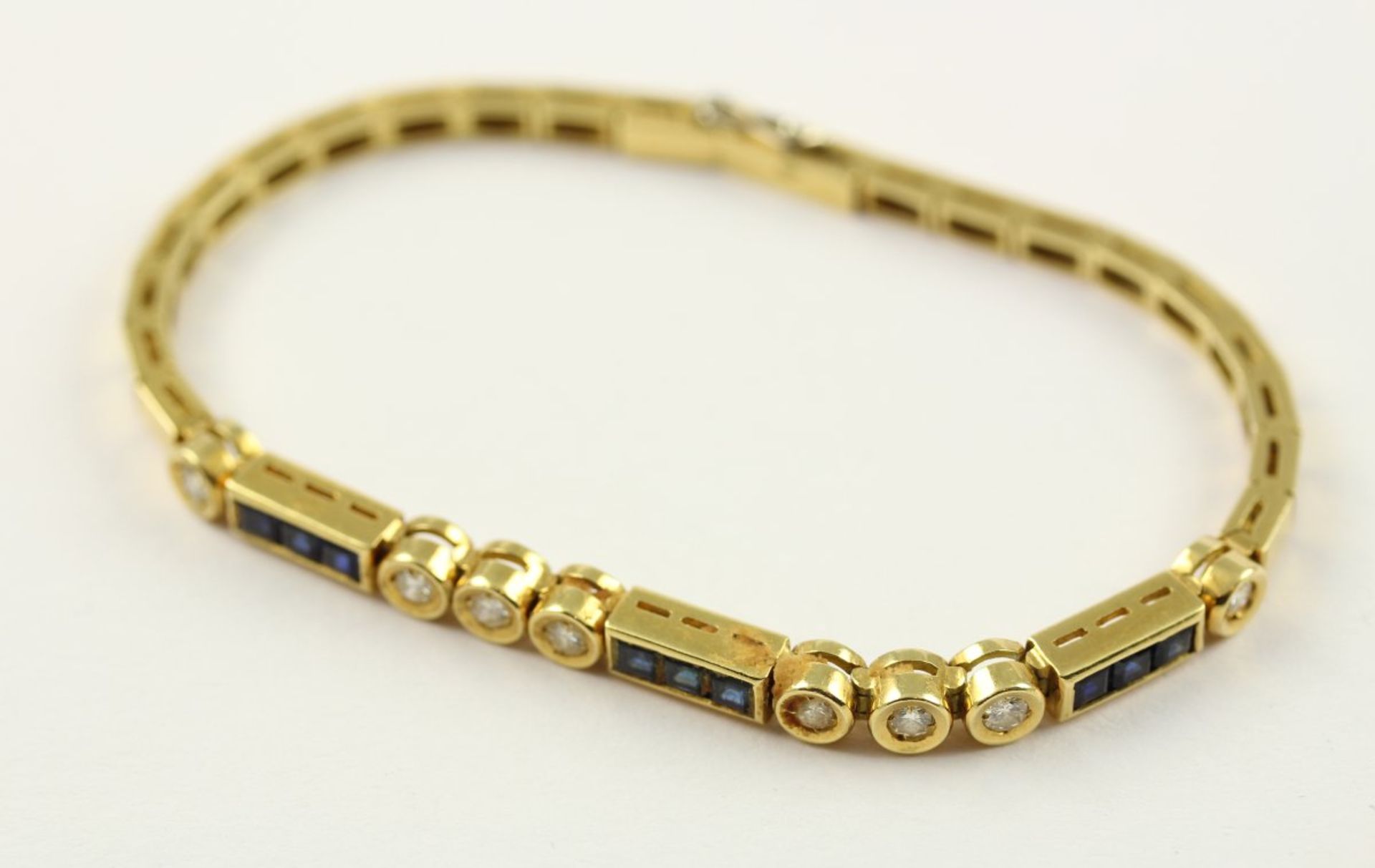 ARMBAND, 750/ooo Gelbgold, besetzt mit 8 Brillanten von zusammen ca. 0,4ct. und 9 Safircarees, L