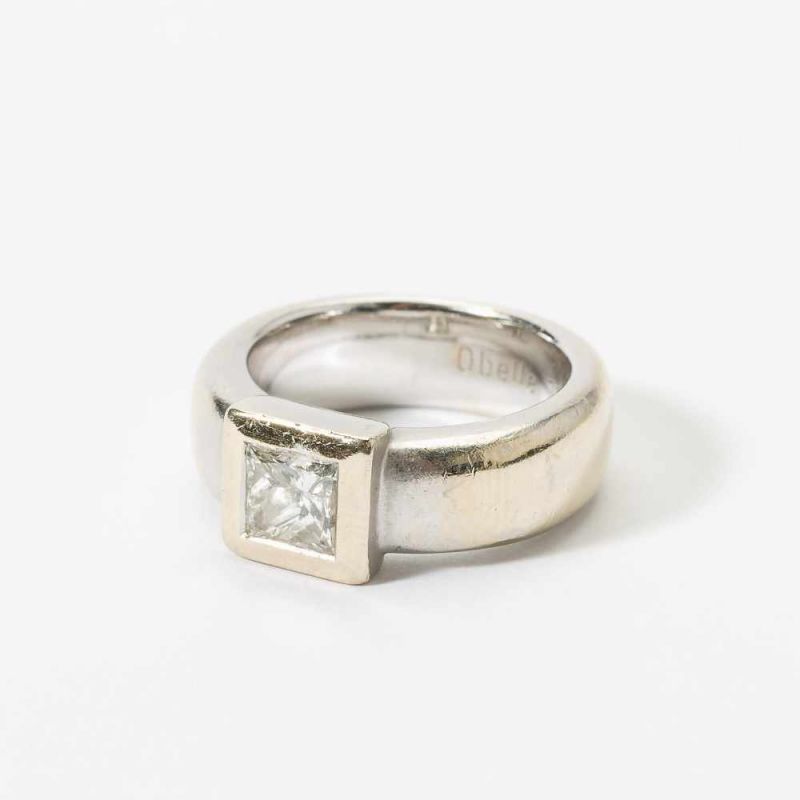 An 18 carat white gold ring 21st century Set with a princess-cut diamond to a wide band, signed