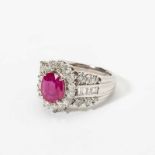 A platinum, diamond and ruby ring 21st century Centered by an oval cut ruby, within circular-cut
