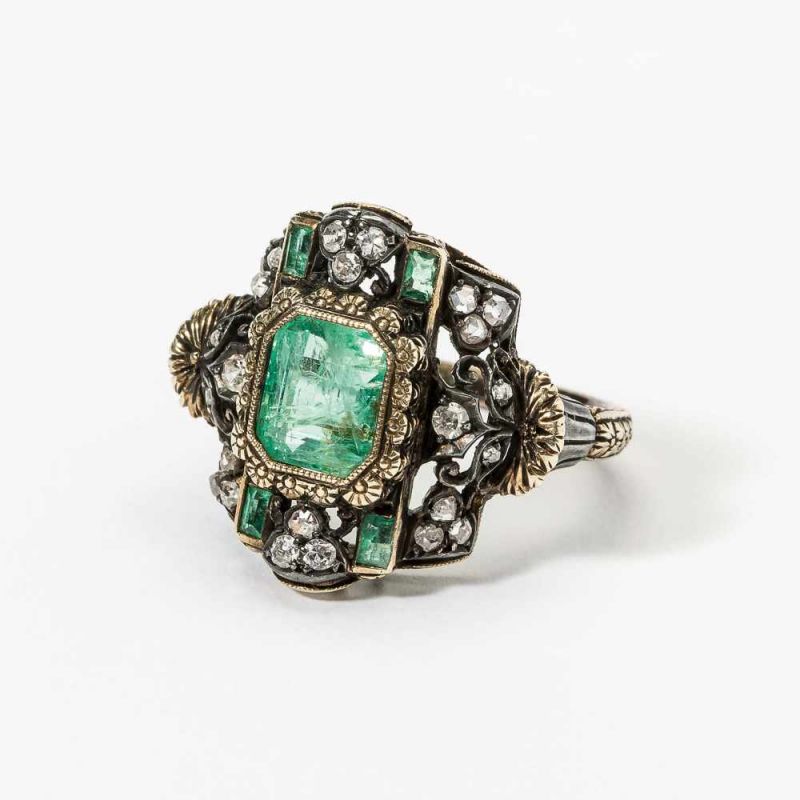 An 18 carat gold, silver, diamond and emerald ring Late 19th century Centered by a step-cut emerald