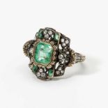 An 18 carat gold, silver, diamond and emerald ring Late 19th century Centered by a step-cut emerald