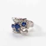 A 14 carat white gold, diamond and sapphire ring Circa 1970 The floral ring set with two old-cut