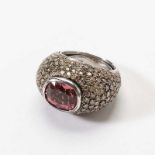 An 18 carat white gold, diamond and pink tourmaline ring Circa 2000 Centered by a cushion-cut pink