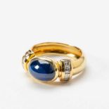 An 18 carat gold and sapphire ring20th centuryCentered by a cabochon-cut blue sapphire, the band set