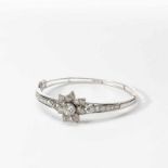 A platinum and 14 carat white gold and diamond bangle20th centuryCentered by a flower head with