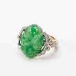 A 14 carat two coloured gold, jade and diamond ring20th centuryCentered by an oval-cut carved jade