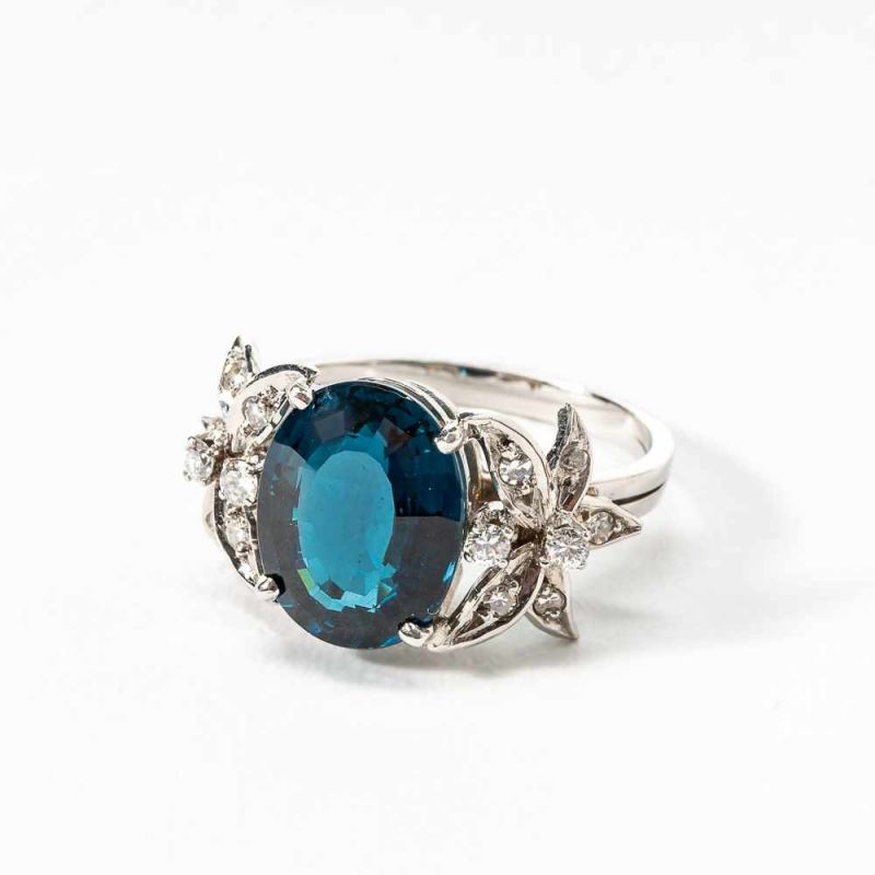 A 14 carat white gold, tourmaline and diamond ringCirca 1980Centered by an oval-cut blue tourmaline,