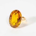 A 14 carat gold and topaz ringCirca 1970Set with an oval-cut gold topaz.Topaz spread approx. 23 x 16