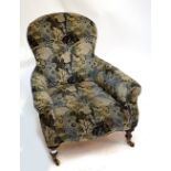 A Victorian low upholstered easy chair raised on turned front legs to castors.