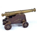 An early 19th century brass model signal cannon on wooden base,