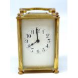 An early 20th century French brass carriage clock with swing loop handle above rectangular white
